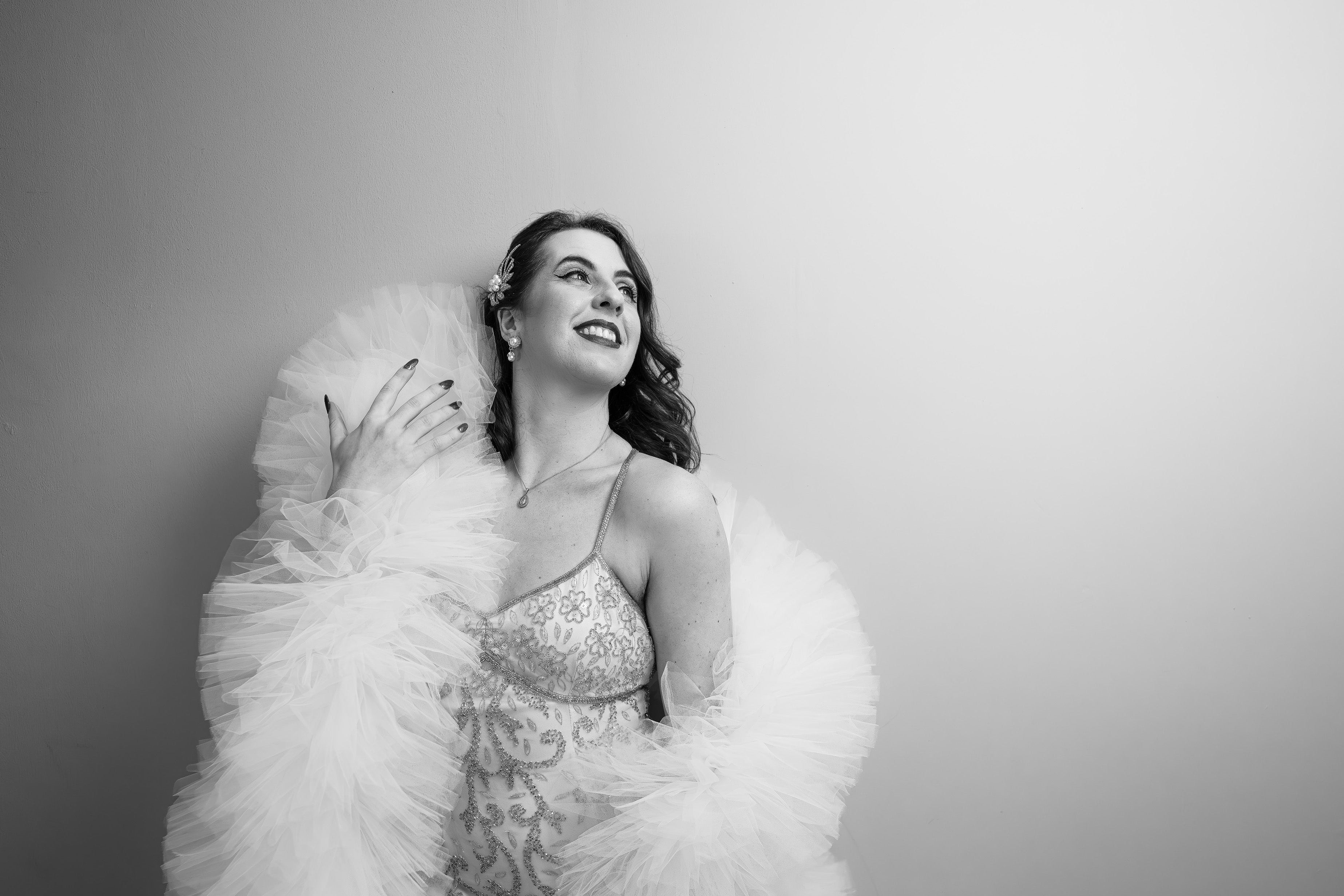 Black and white photo of a woman in a glamorous wedding dress with a large ivory boa.